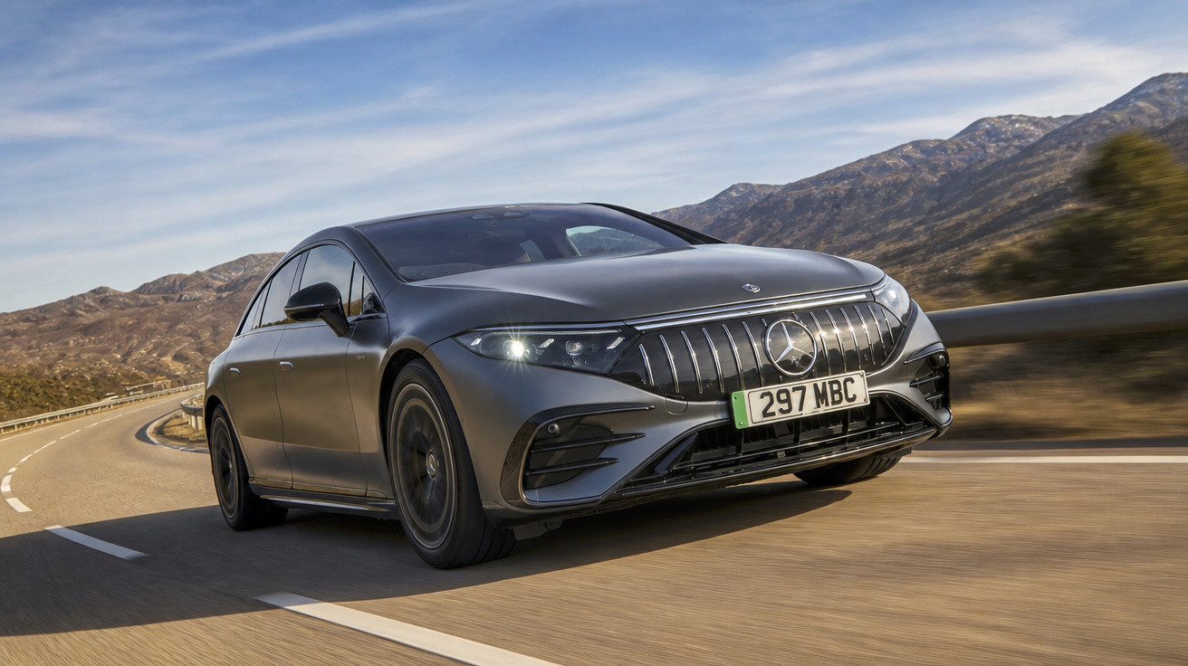 Carro Mercedes-Benz elétrico cinza a circular numa estrada sinuosa com montanhas ao fundo.