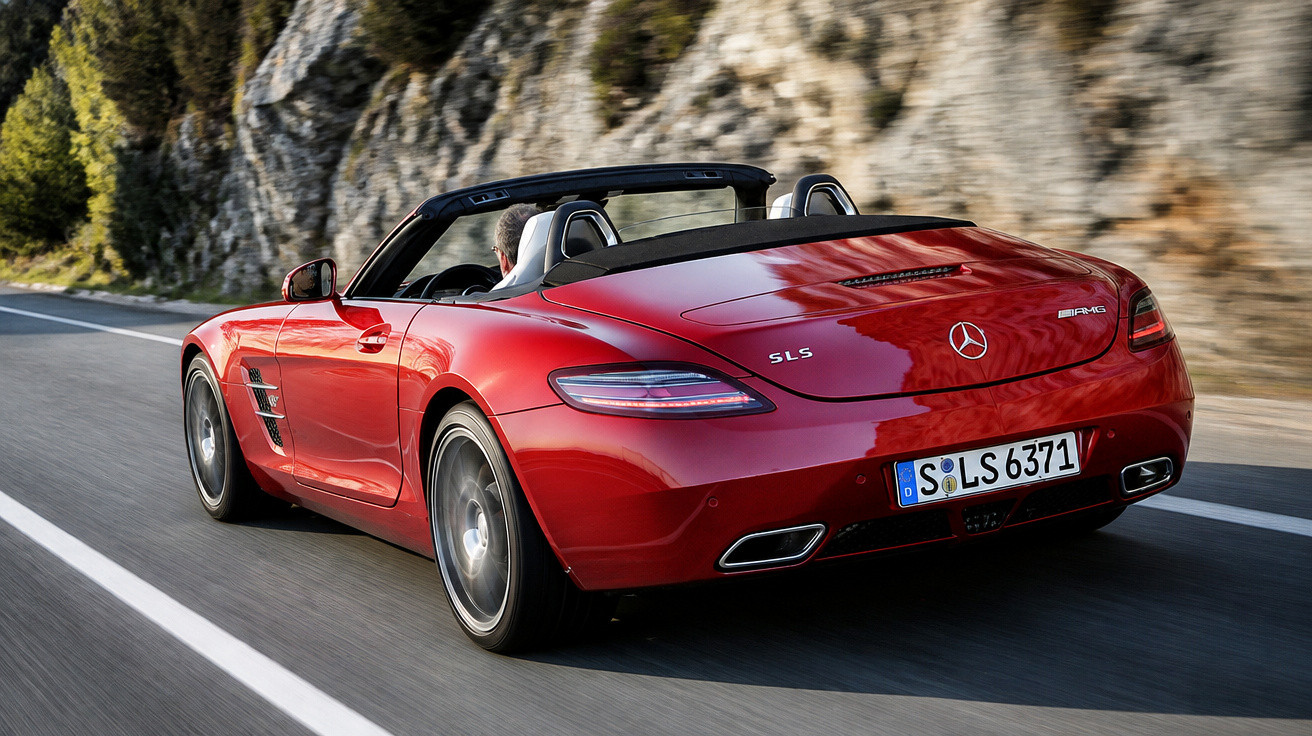 Carro desportivo descapotável vermelho Mercedes SLS AMG em estrada junto a rochas.