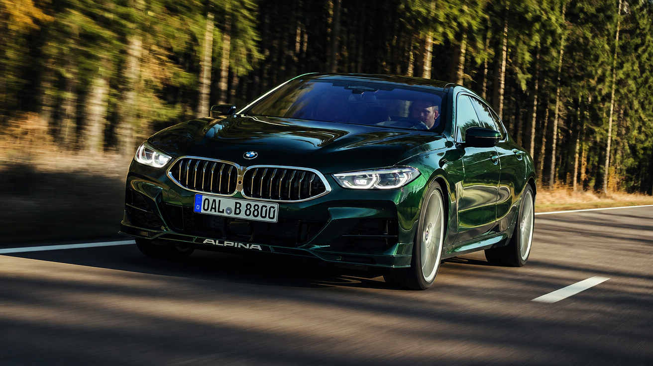 Carro desportivo BMW Alpina verde em movimento numa estrada rodeada de pinheiros.
