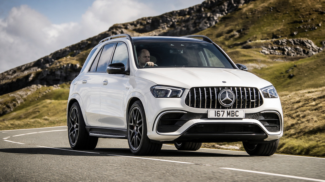 Carro Mercedes-Benz branco a circular numa estrada sinuosa com montanhas ao fundo.