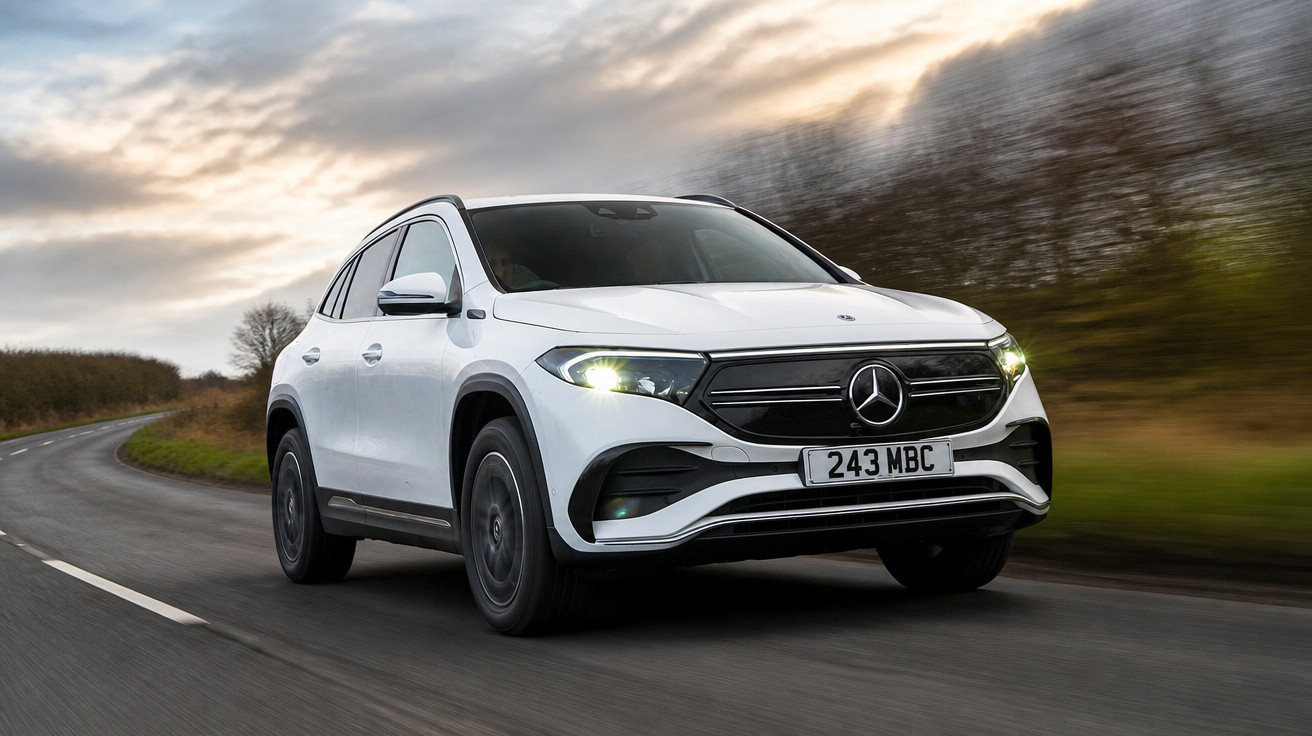 Carro elétrico Mercedes-Benz branco a circular numa estrada curva com faróis ligados ao entardecer.