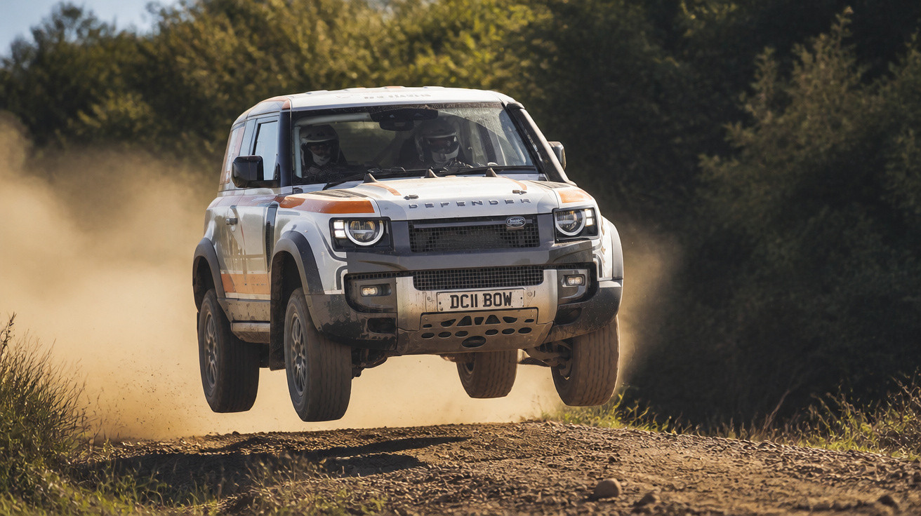 Carro off-road branco em movimento, a voar sobre estrada de terra em ambiente florestal.