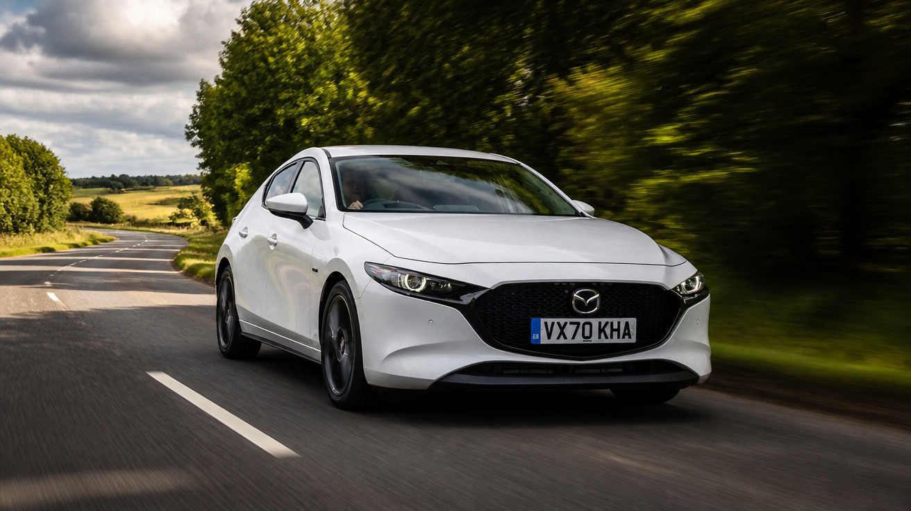 Carro branco Mazda 3 a circular numa estrada sinuosa rodeada por árvores e vegetação.