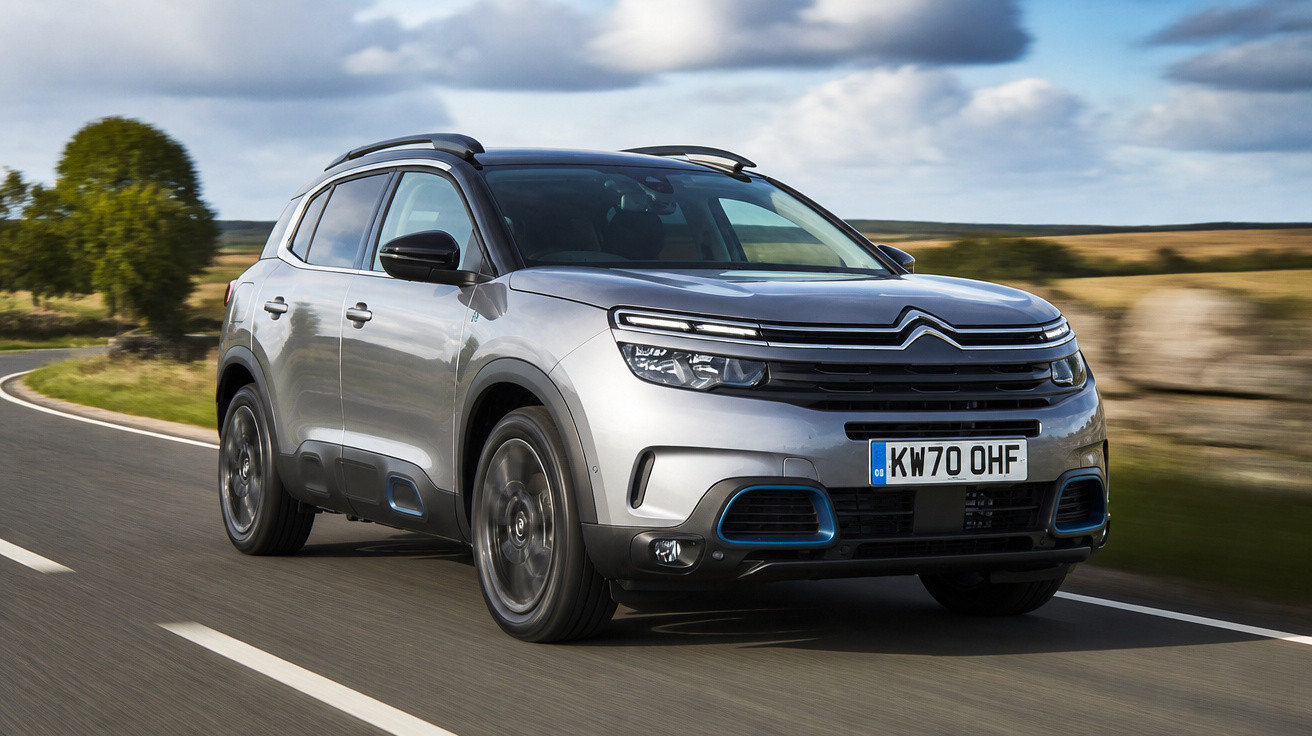 Carro Citroën C5 Aircross prata a circular numa estrada rural com árvore e campos ao fundo.