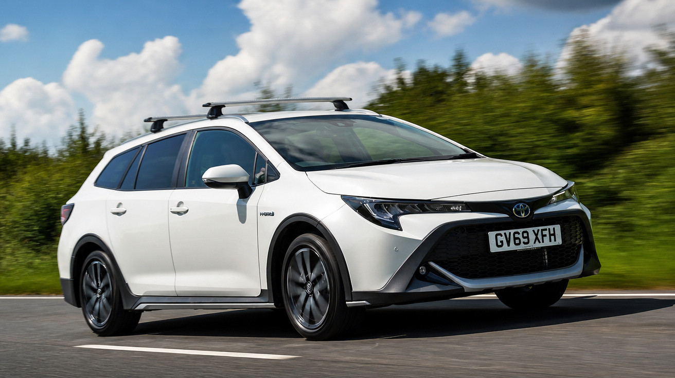 Carro Toyota Corolla Touring Sports híbrido branco em estrada com vegetação ao fundo e céu nublado.