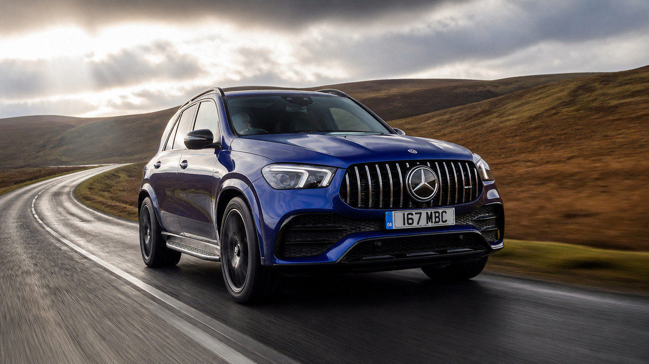 Carro Mercedes-Benz azul a circular numa estrada curva em paisagem montanhosa com céu nublado.