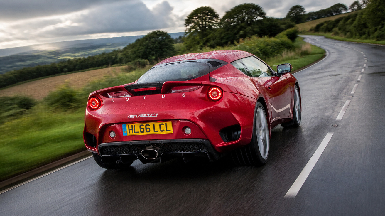 Carro desportivo vermelho Lotus GT410 a conduzir numa estrada molhada sinuosa em zona rural.