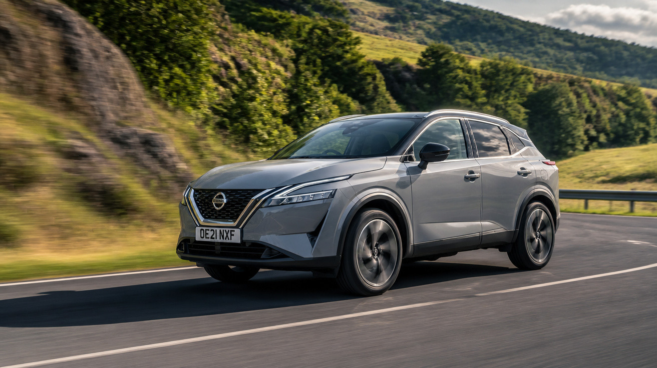 Carro SUV cinza da Nissan em movimento numa estrada sinuosa com paisagem verde ao fundo.