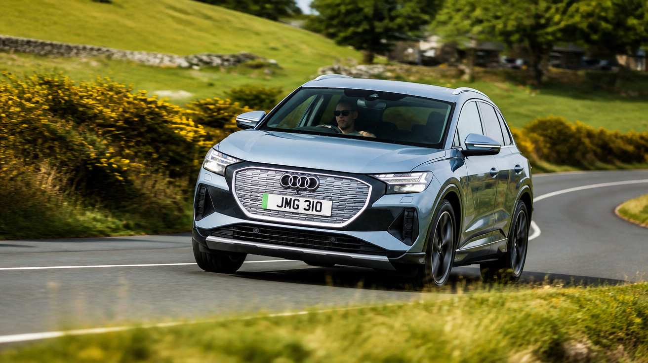 Carro Audi elétrico cinza a circular numa estrada sinuosa rodeada de vegetação verde.