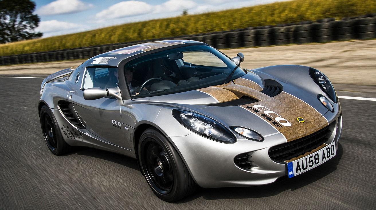 Carro desportivo cinzento com decoração castanha conduzido numa estrada curva com céu azul e nuvens.