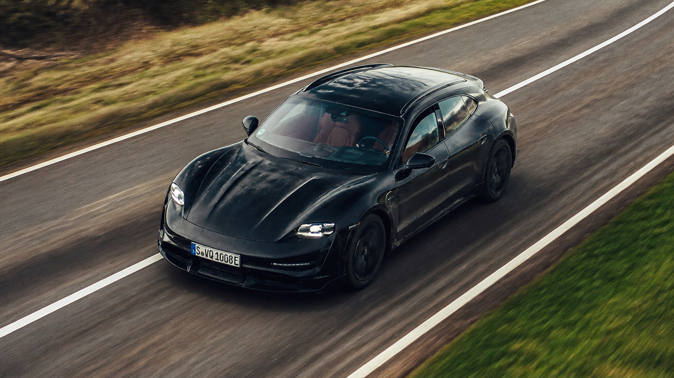 Carro elétrico preto a circular numa estrada asfaltada entre relva e vegetação.