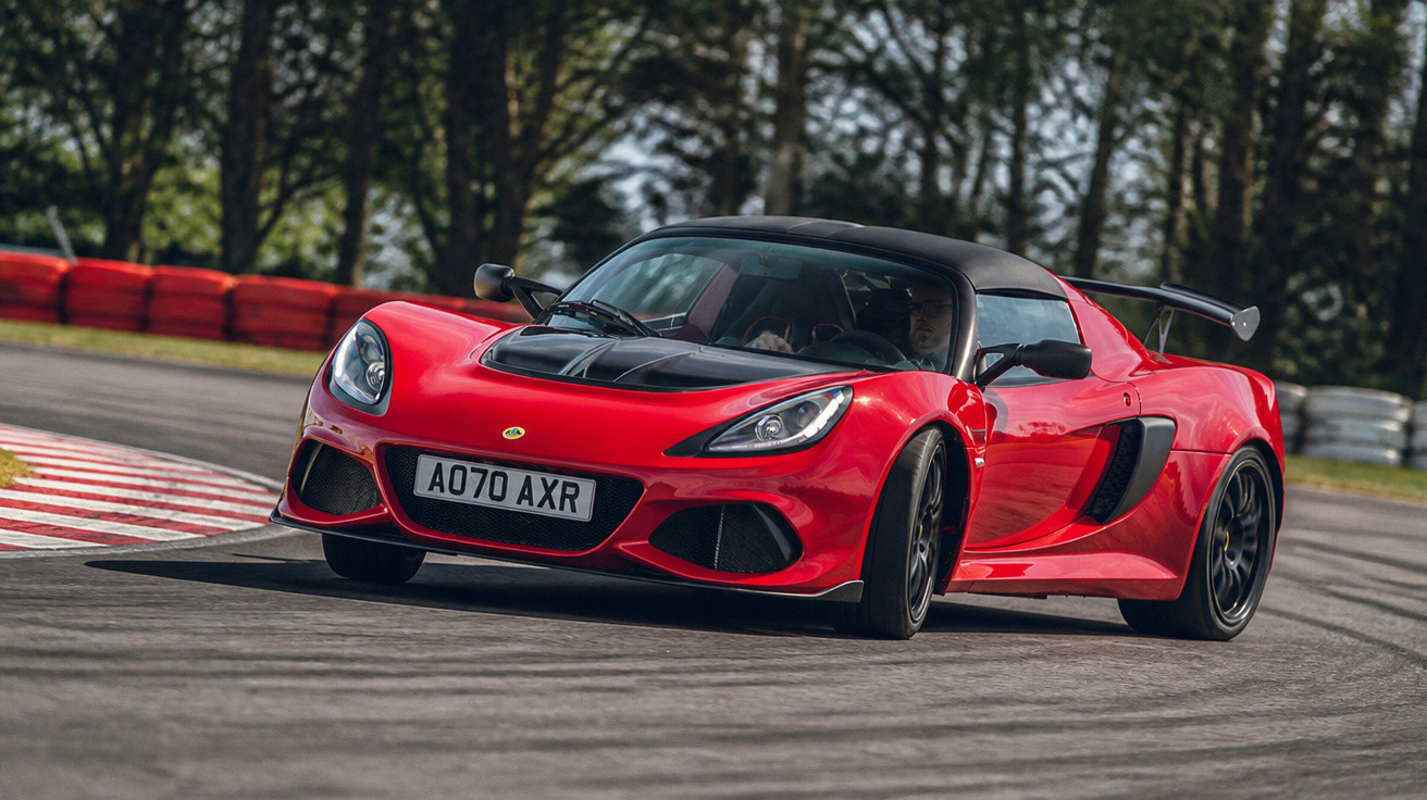 Carro desportivo vermelho a acelerar numa curva de circuito com árvores ao fundo.