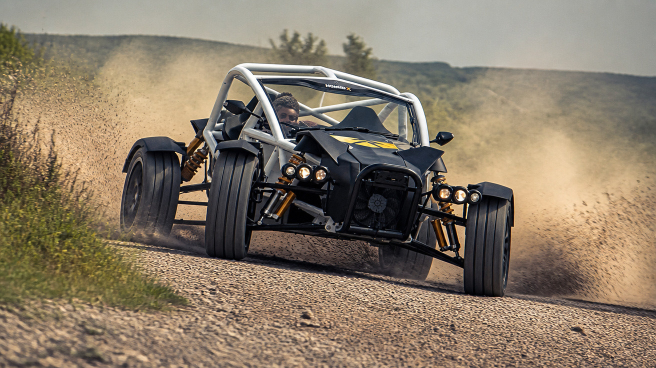 Carro buggy preto em alta velocidade a levantar poeira numa estrada de terra batida.