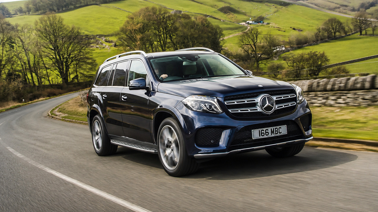 Mercedes-Benz SUV azul escuro a circular numa estrada sinuosa rodeada de campos verdes e árvores.