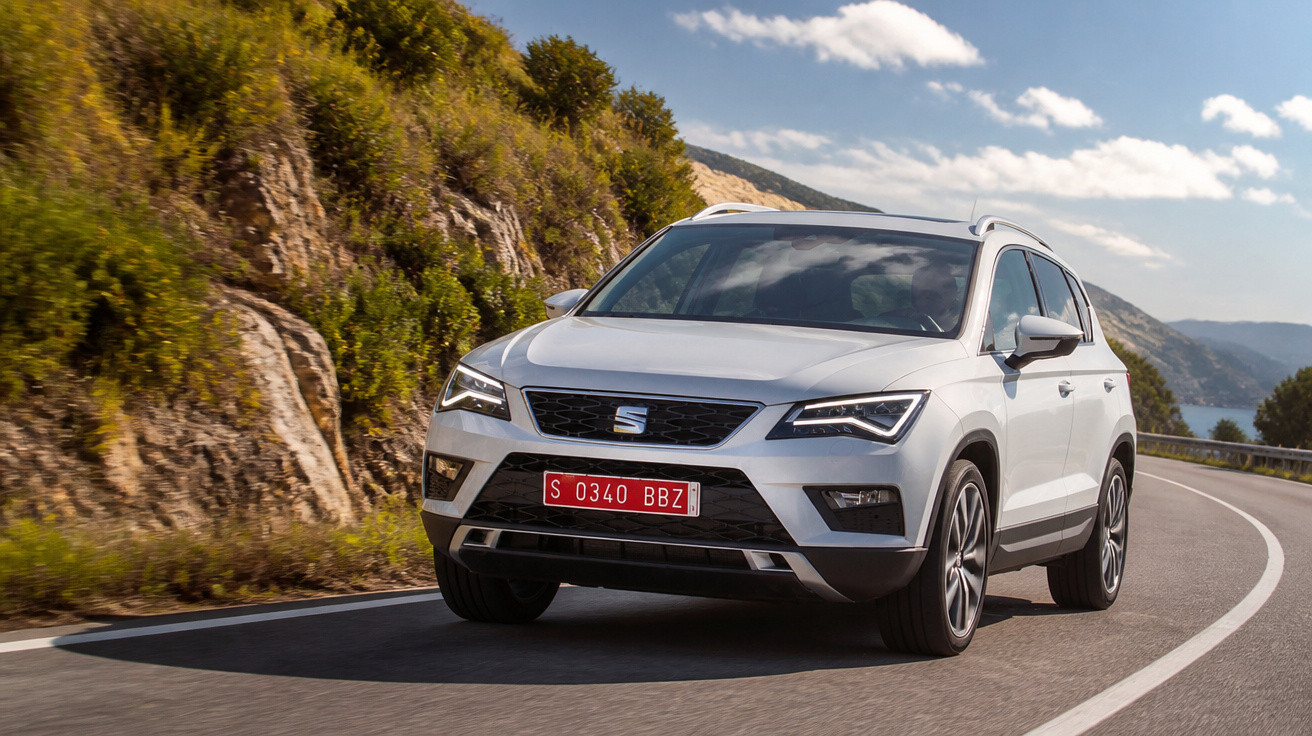Carro SUV branco da marca SEAT a circular numa estrada sinuosa junto a colinas rochosas.
