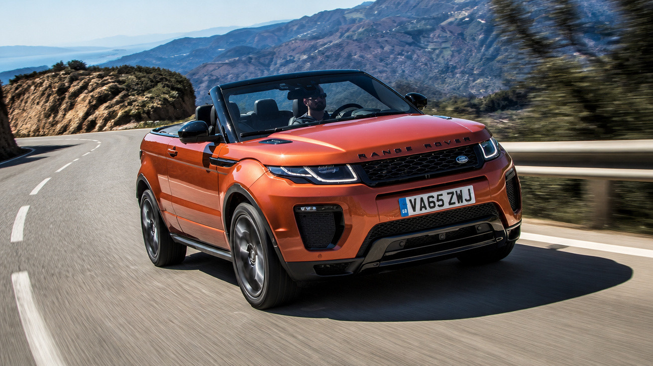 Carro Range Rover Evoque descapotável laranja a conduzir numa estrada de montanha sinuosa.