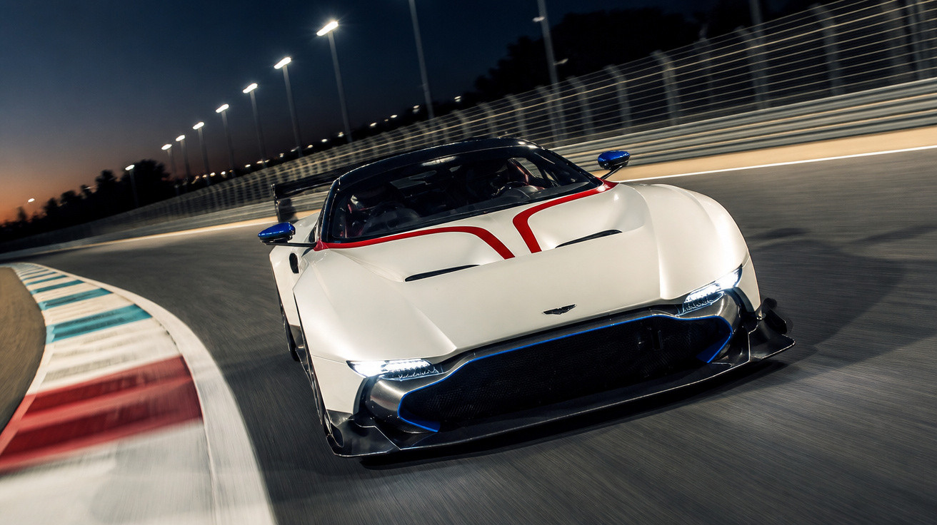 Carro desportivo branco a alta velocidade numa pista de corrida iluminada à noite.