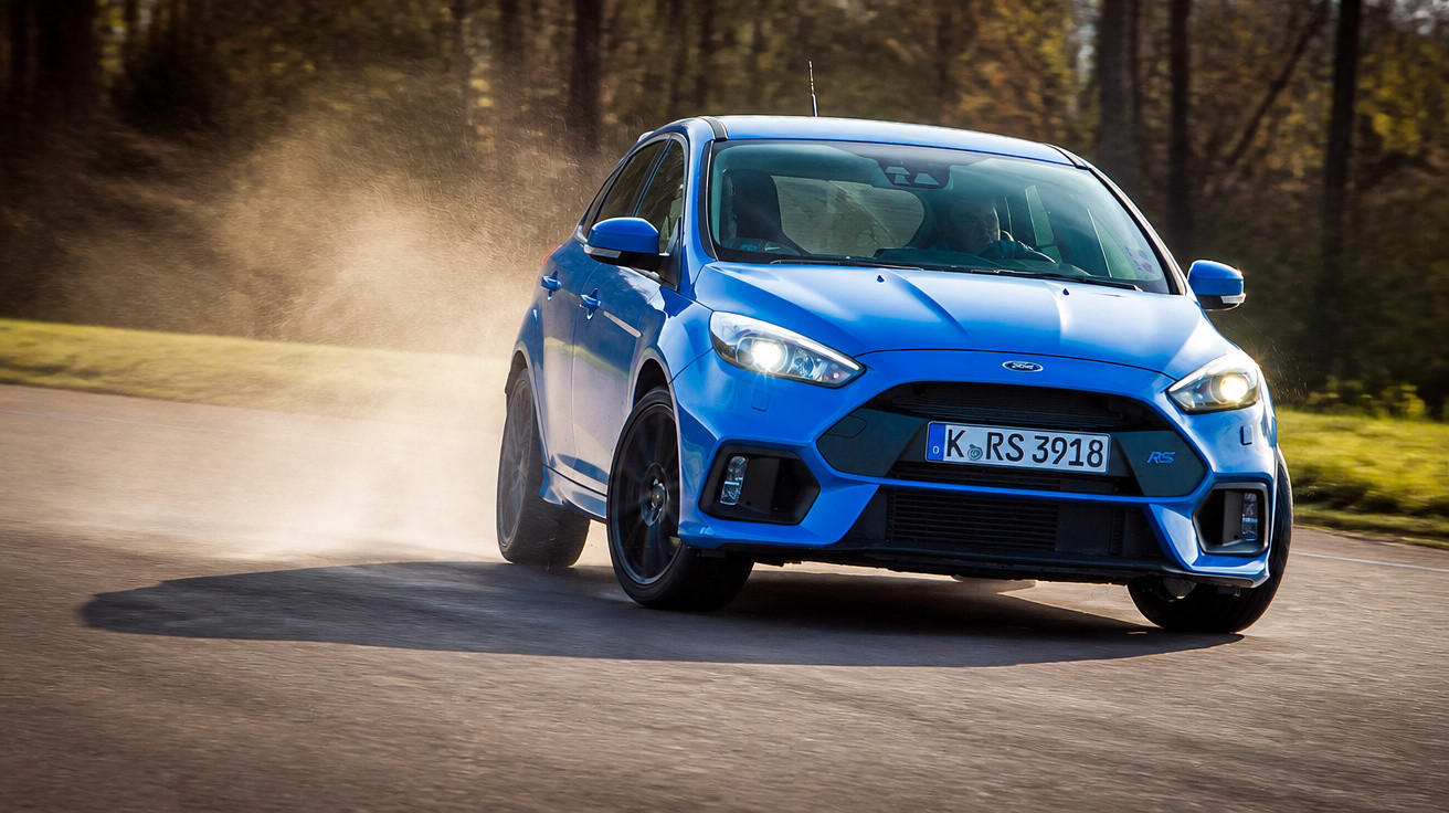 Carro desportivo azul a fazer uma curva rápida numa estrada com pó a levantar-se atrás.