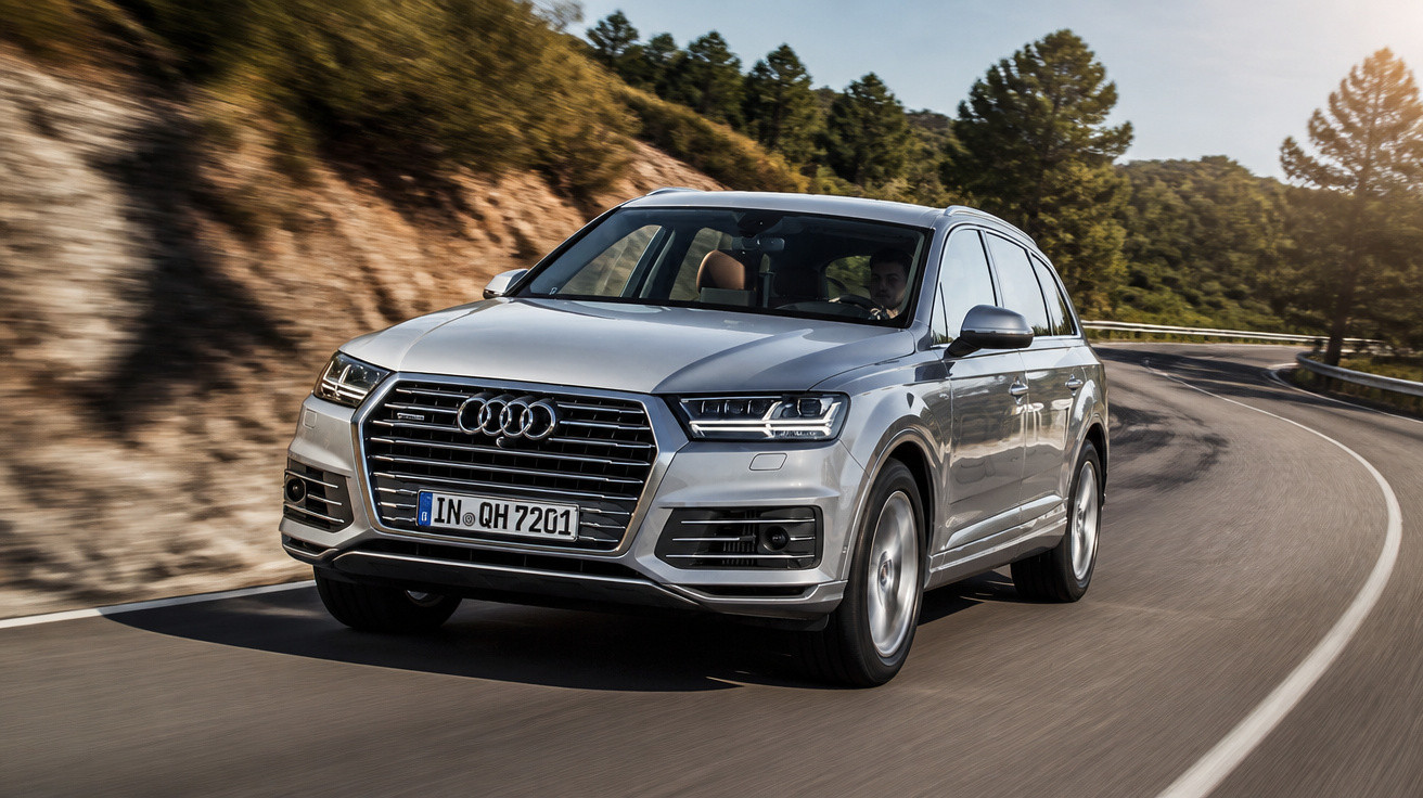 Carro Audi SUV cinza a circular numa estrada sinuosa de montanha com árvores e sol.