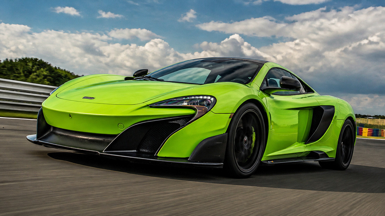 Carro desportivo verde-limão a circular numa pista de corrida sob céu nublado.