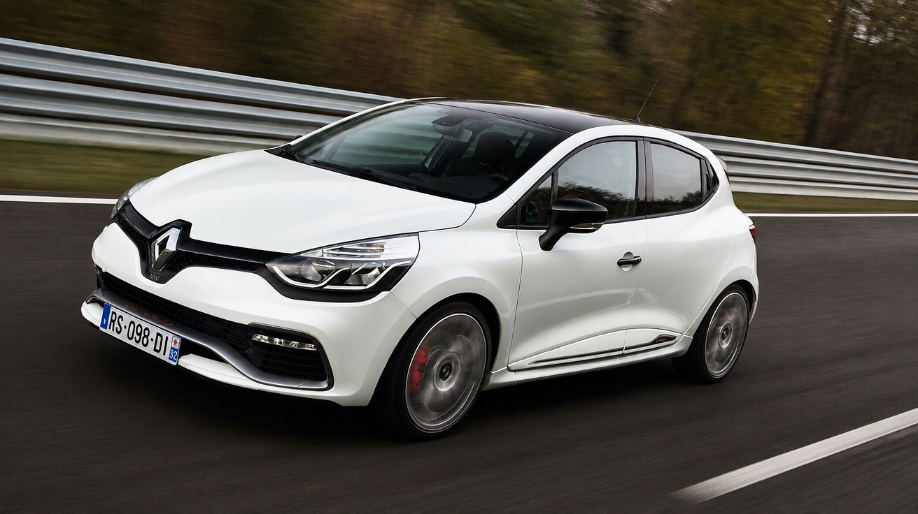 Carro desportivo branco em contração numa estrada com proteção metálica e árvores ao fundo.