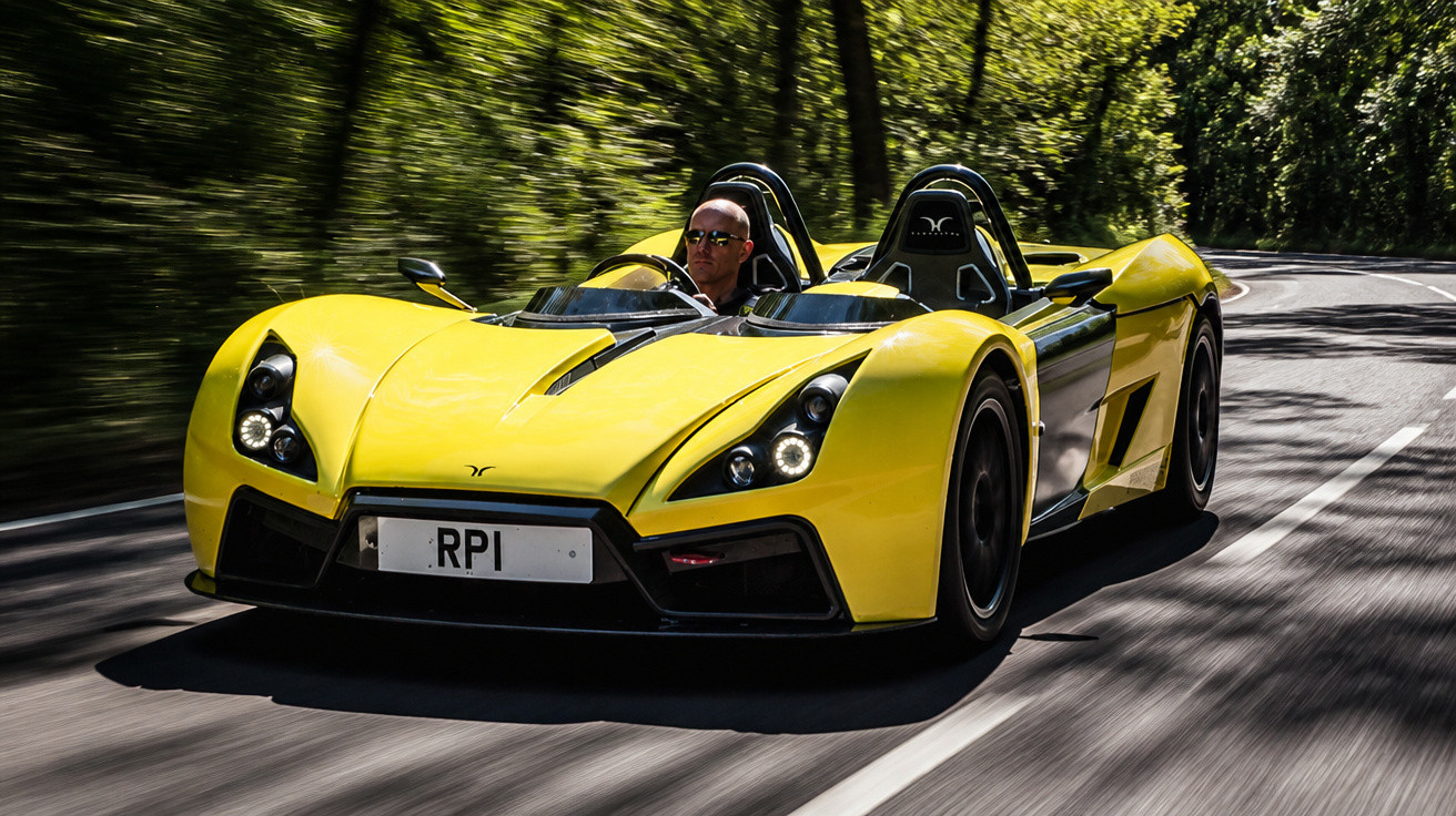 Carro desportivo amarelo a circular numa estrada sinuosa rodeada de árvores verdes.