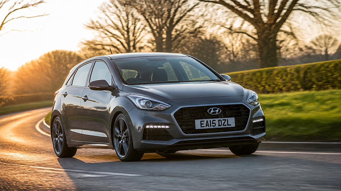 Carro cinza Hyundai em estrada sinuosa ao pôr do sol com árvores e relva ao fundo.