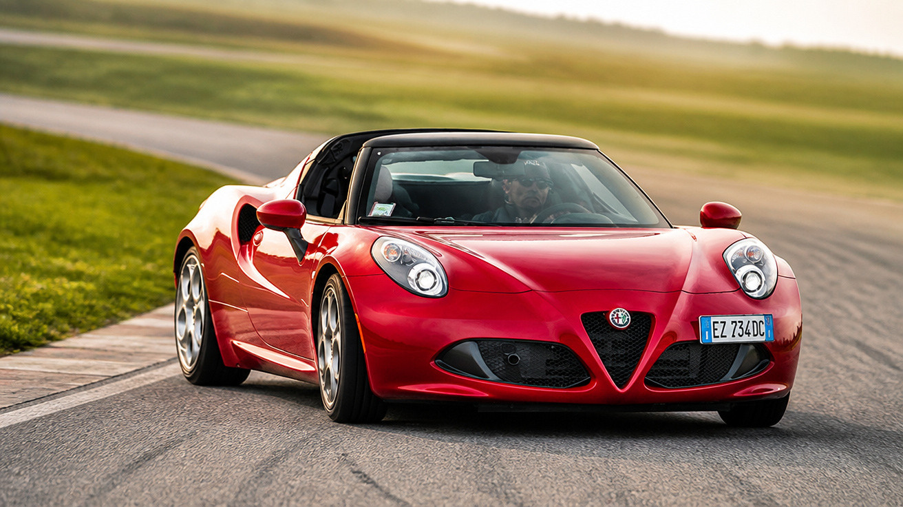 Carro desportivo vermelho Alfa Romeo a circular numa pista de corrida com paisagem verde ao fundo.