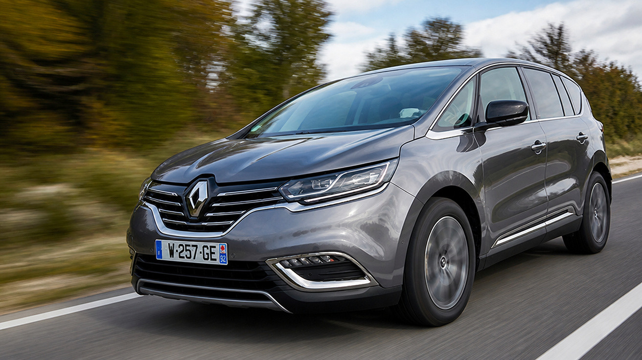 Carro cinzento Renault a circular numa estrada ladeada de árvores e céu parcialmente nublado.