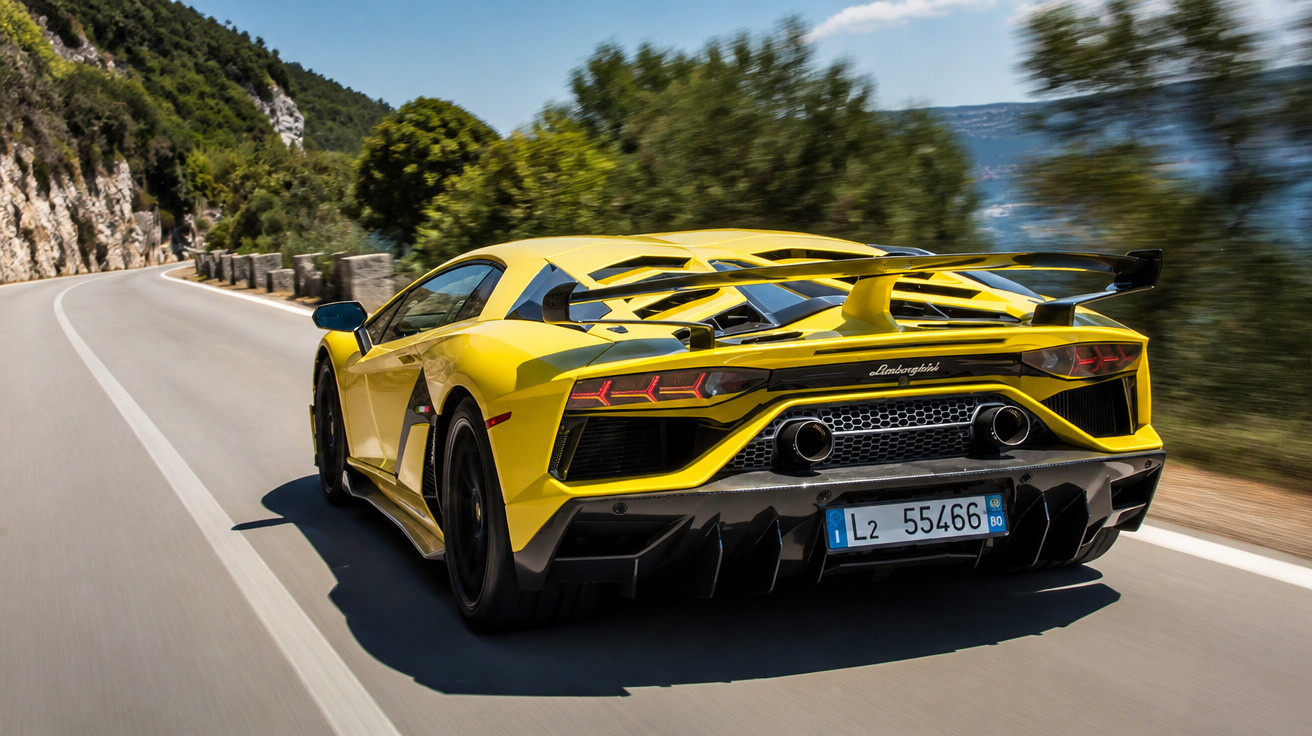 Automóvel desportivo amarelo a circular numa estrada sinuosa entre montanhas e mar.