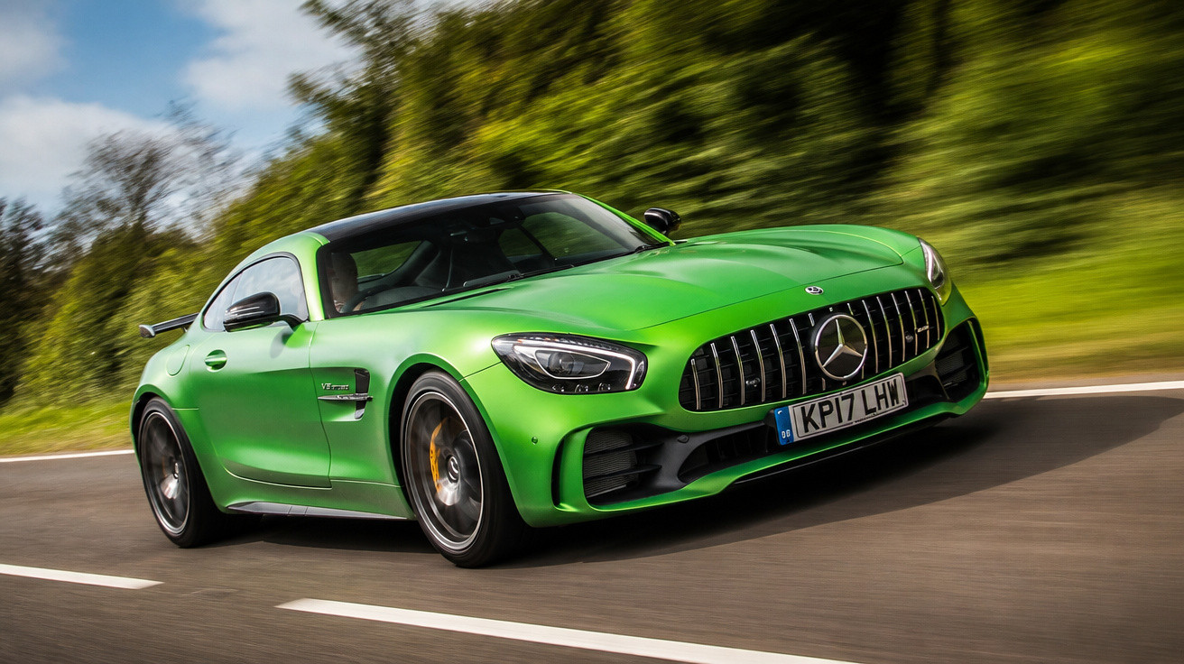 Carro desportivo verde Mercedes-Benz AMG GT a alta velocidade numa estrada rodeada de árvores.